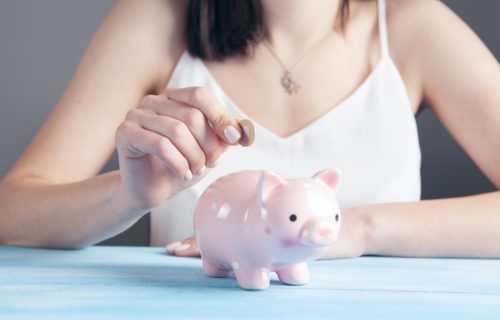 Savings: Woman putting money in a piggy bank